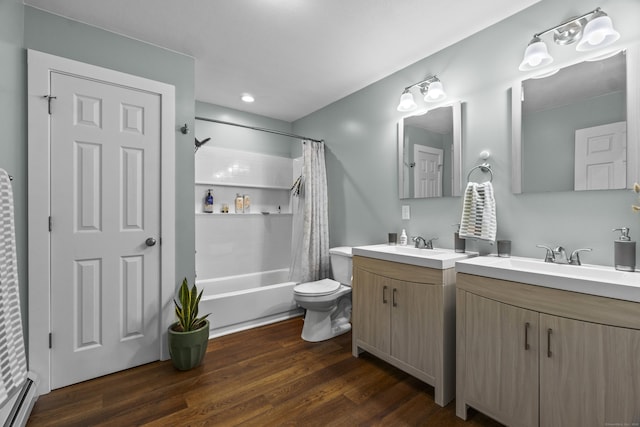 full bathroom featuring shower / bath combo, a baseboard heating unit, a sink, and wood finished floors