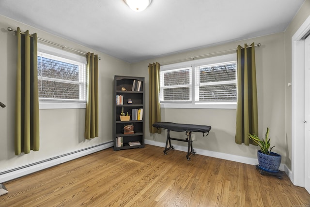 sitting room with baseboards, baseboard heating, and light wood-style floors