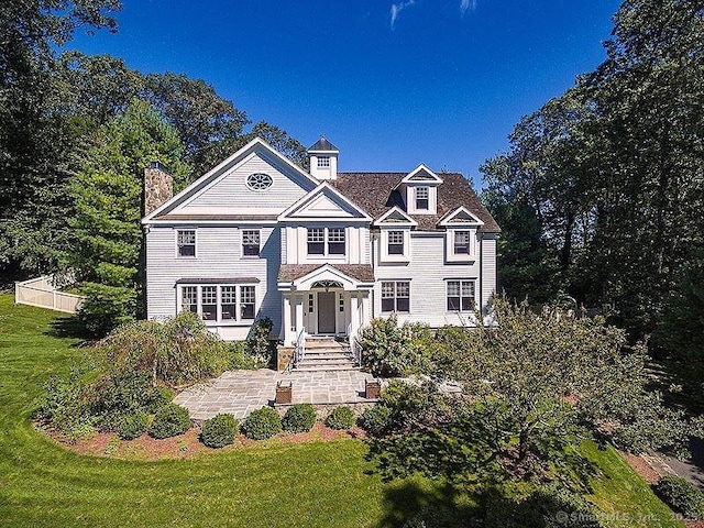 view of front of house with fence, a chimney, and a front lawn