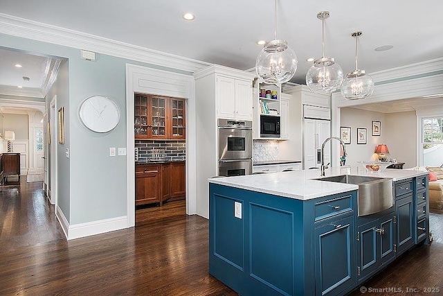 kitchen with blue cabinetry, light countertops, hanging light fixtures, white cabinetry, and built in appliances