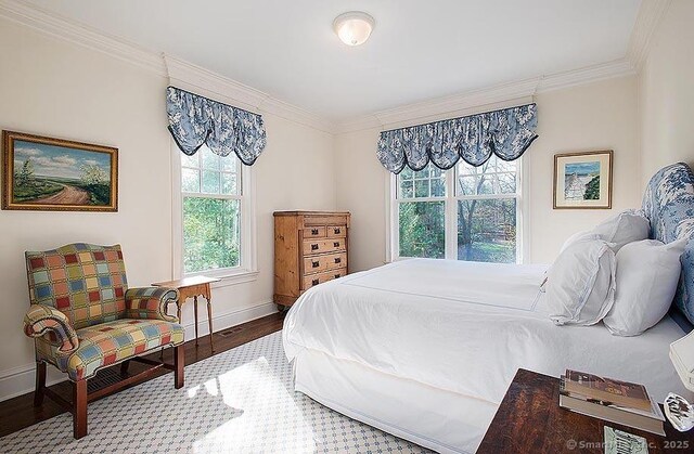 bedroom featuring baseboards, wood finished floors, and crown molding