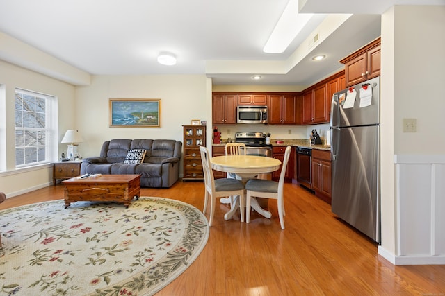 kitchen featuring light wood finished floors, stainless steel appliances, light countertops, and open floor plan