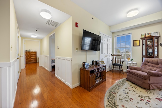 living room with visible vents, wood finished floors, and wainscoting