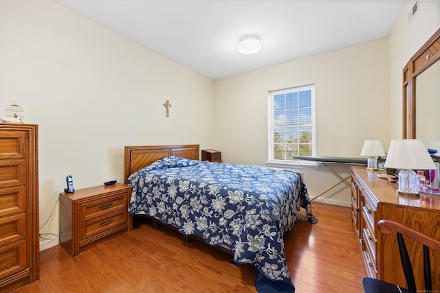 bedroom featuring baseboards, visible vents, and light wood finished floors