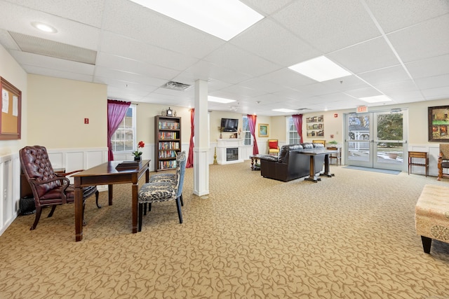 living room featuring french doors, a wainscoted wall, a fireplace, a paneled ceiling, and carpet flooring