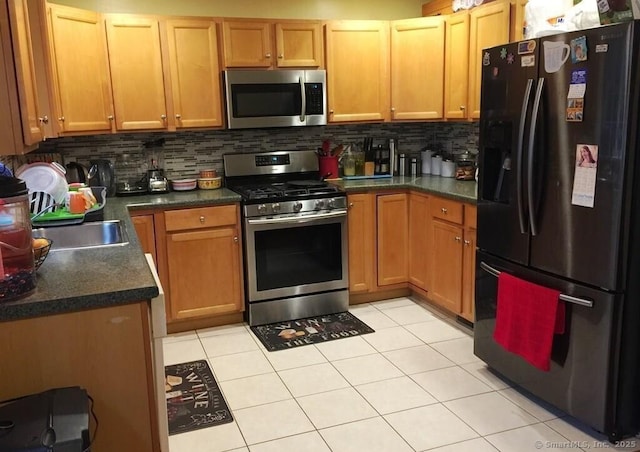 kitchen featuring stainless steel appliances, tasteful backsplash, dark countertops, and a sink