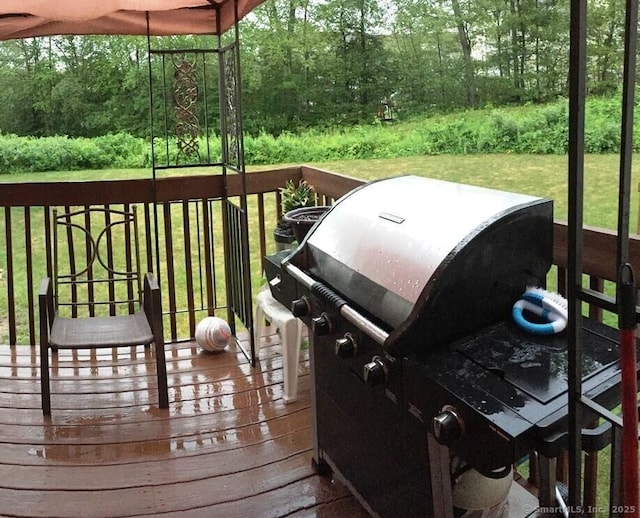 wooden deck featuring a yard and a grill