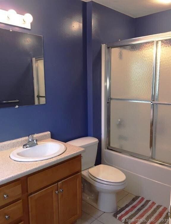 full bathroom with toilet, bath / shower combo with glass door, vanity, and tile patterned floors