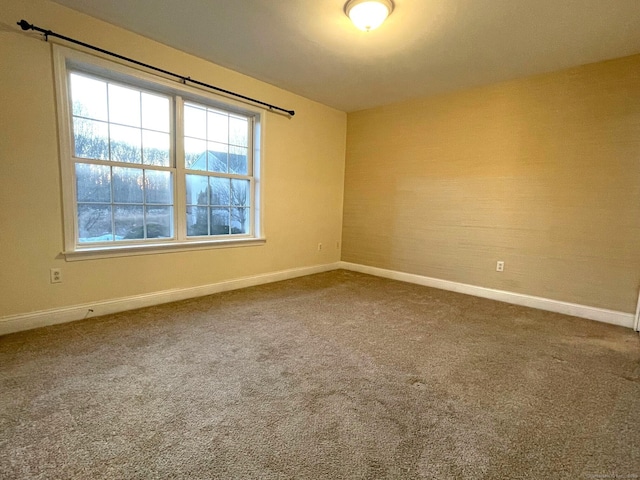 unfurnished room featuring carpet and baseboards