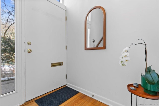 doorway to outside with wood finished floors, a wealth of natural light, and baseboards