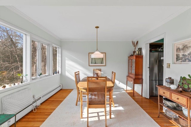 dining room with ornamental molding, a baseboard radiator, and wood finished floors