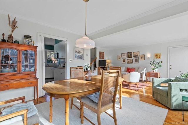 dining area featuring stairway, light wood-type flooring, and crown molding