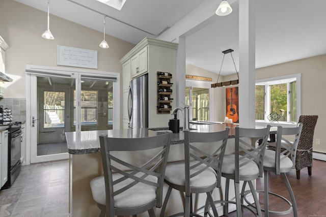 kitchen featuring freestanding refrigerator, black electric range oven, vaulted ceiling with skylight, and a breakfast bar area