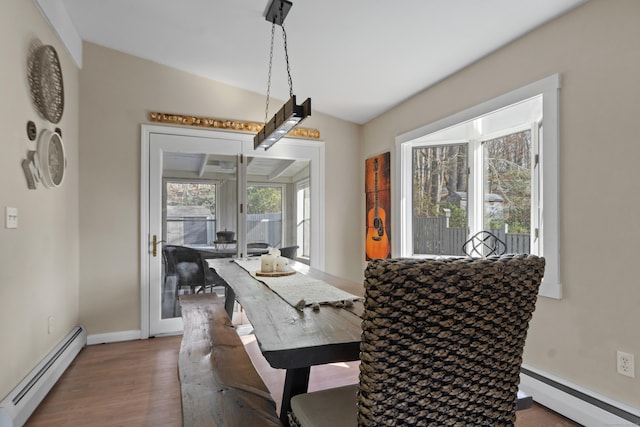 dining room with a baseboard heating unit, baseboard heating, wood finished floors, and baseboards