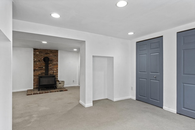 finished below grade area featuring a wood stove, carpet, baseboards, and recessed lighting