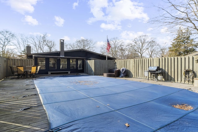 view of swimming pool featuring a deck, a fenced backyard, and a grill