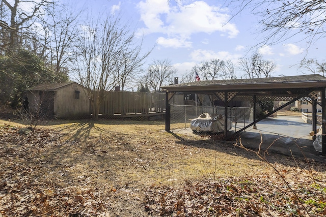 view of yard featuring an outbuilding, fence, and a detached carport