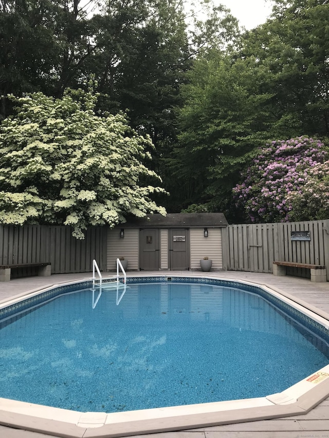 view of swimming pool featuring fence, a fenced in pool, and an outbuilding