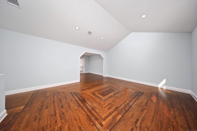 additional living space with arched walkways, visible vents, vaulted ceiling, and baseboards