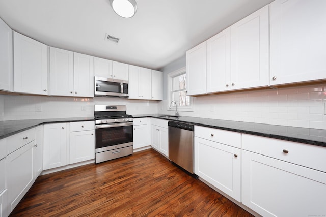 kitchen featuring dark wood finished floors, stainless steel appliances, visible vents, white cabinets, and a sink