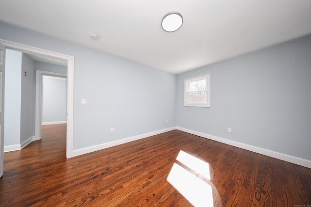 spare room featuring baseboards and dark wood finished floors