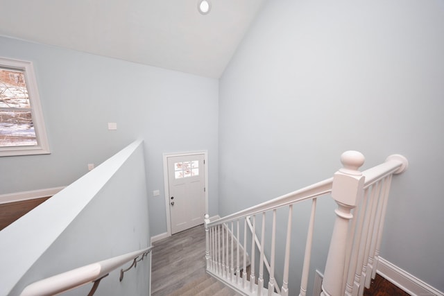 stairs with baseboards, vaulted ceiling, and wood finished floors