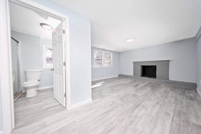 unfurnished living room with light wood-type flooring, a fireplace, and baseboards