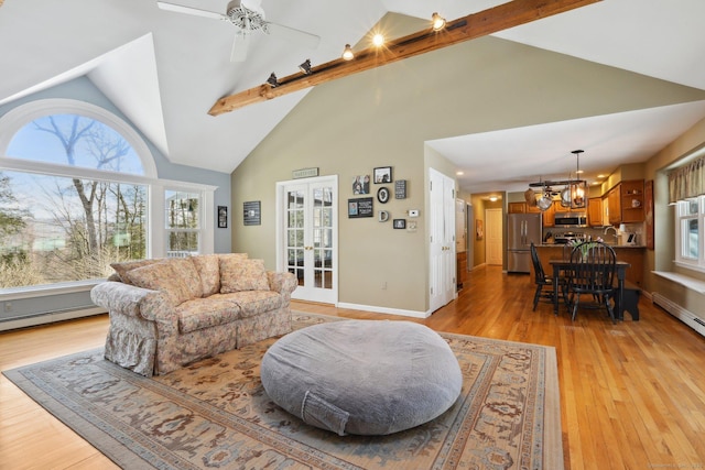 living room featuring ceiling fan with notable chandelier, a baseboard heating unit, baseboards, french doors, and light wood-type flooring