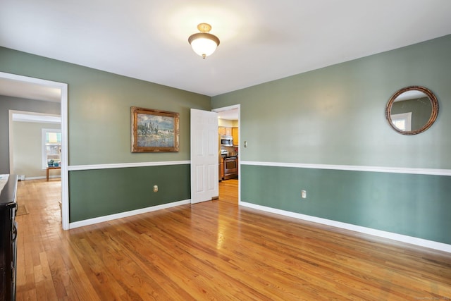 spare room featuring light wood-type flooring and baseboards