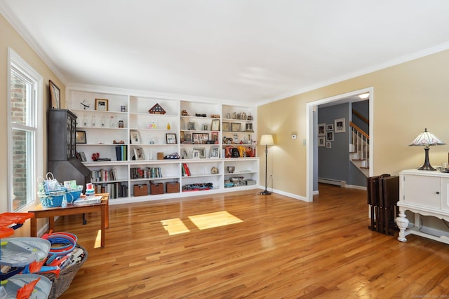 living area featuring baseboards, light wood-style flooring, ornamental molding, stairs, and baseboard heating