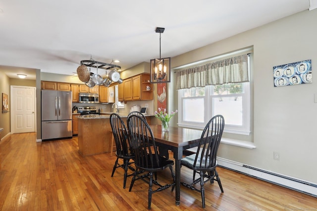 dining room featuring a baseboard heating unit, a chandelier, baseboards, and wood finished floors