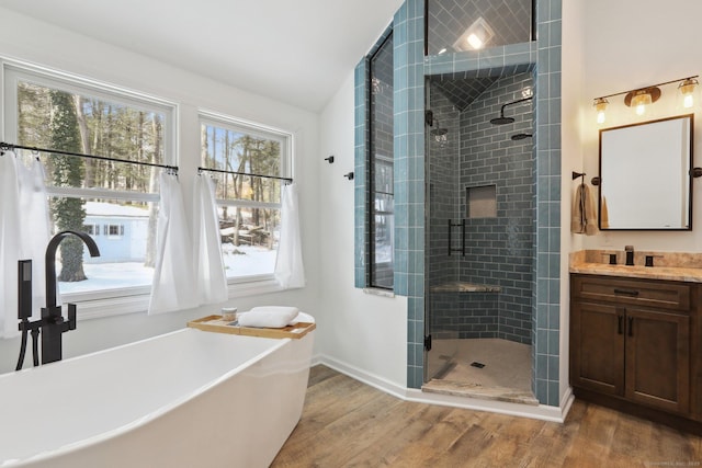 full bath with wood finished floors, vanity, baseboards, a freestanding bath, and a stall shower