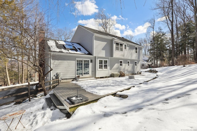 snow covered property with a deck, a chimney, and entry steps