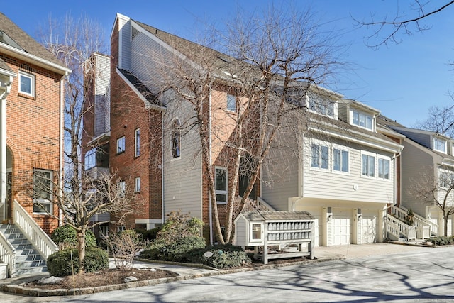 view of front facade featuring driveway, a garage, and stairway