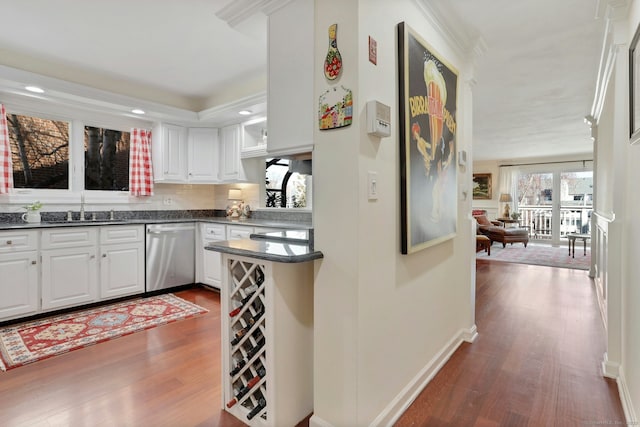 kitchen with a sink, dark countertops, white cabinets, and dishwasher