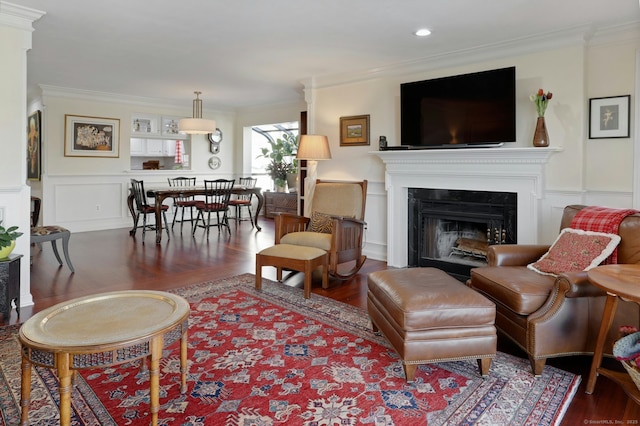 living room with ornamental molding, a fireplace, a decorative wall, and wood finished floors