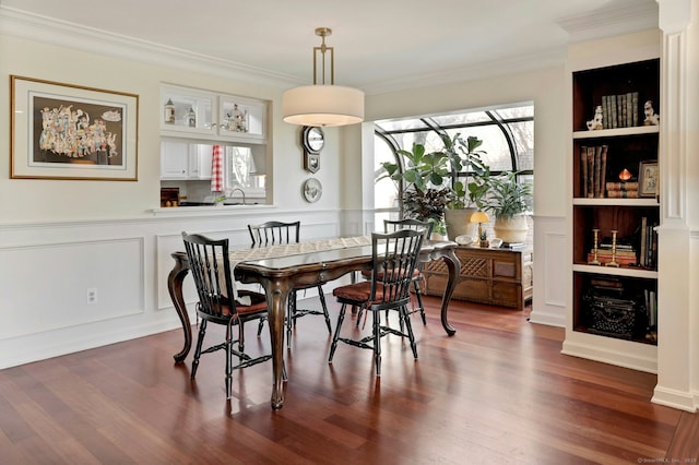 dining room with dark wood-style floors, built in features, and crown molding