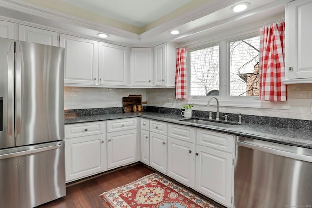 kitchen with stainless steel appliances, dark wood-type flooring, a sink, white cabinetry, and decorative backsplash