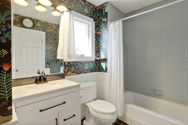 bathroom with a wainscoted wall, shower / bath combination with curtain, toilet, vanity, and wallpapered walls