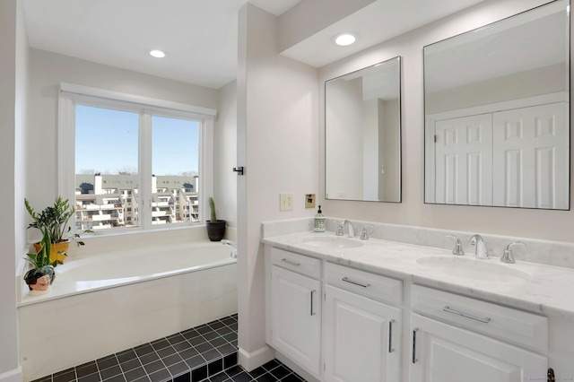 bathroom with double vanity, a sink, a bath, and tile patterned floors