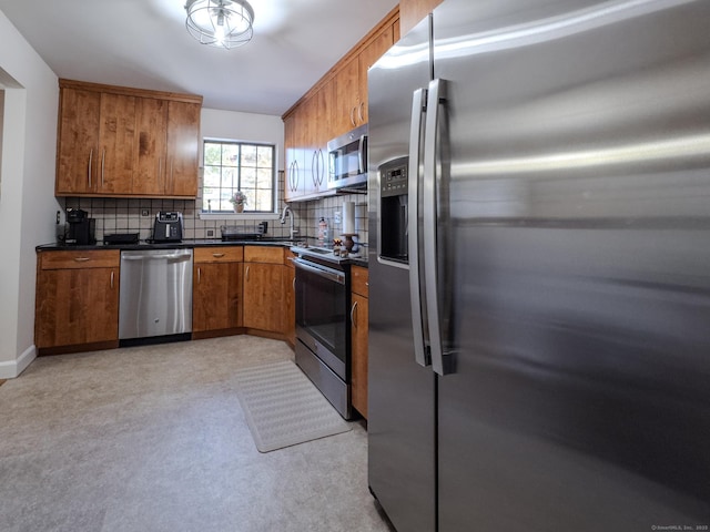 kitchen featuring baseboards, brown cabinetry, dark countertops, stainless steel appliances, and backsplash