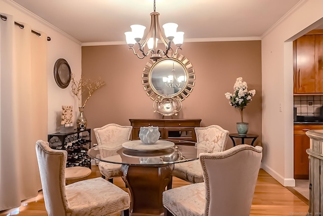 dining room with light wood-type flooring, baseboards, ornamental molding, and a chandelier