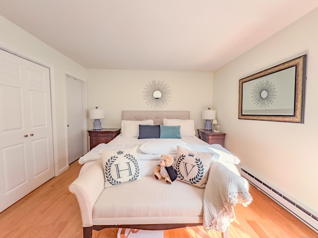 bedroom featuring light wood finished floors and a baseboard radiator