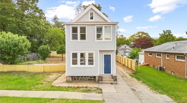 rear view of house with entry steps, a yard, and fence