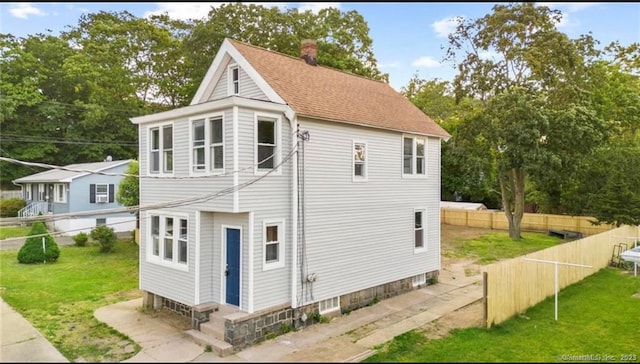 exterior space with entry steps, fence, a chimney, and a lawn