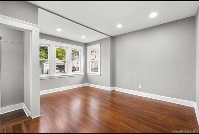 unfurnished room featuring dark wood-type flooring, recessed lighting, and baseboards