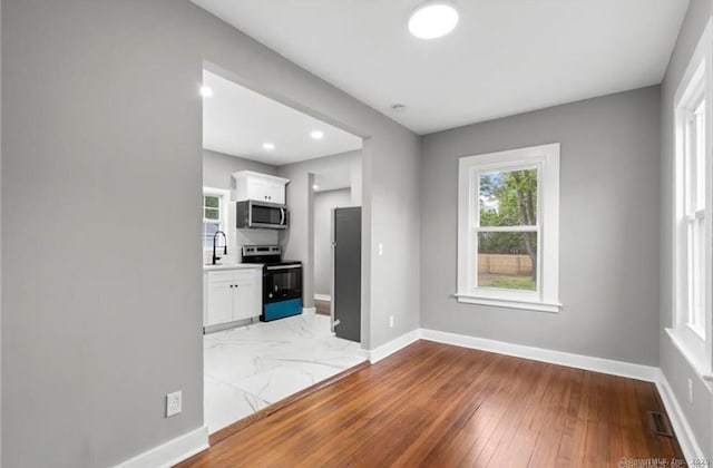 kitchen featuring stainless steel appliances, visible vents, light wood-style flooring, white cabinetry, and baseboards