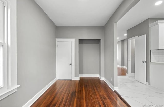 hall featuring marble finish floor, baseboards, and recessed lighting