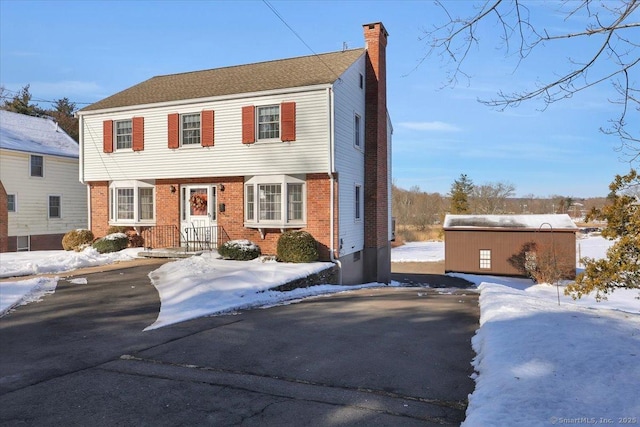 colonial home featuring brick siding and a chimney