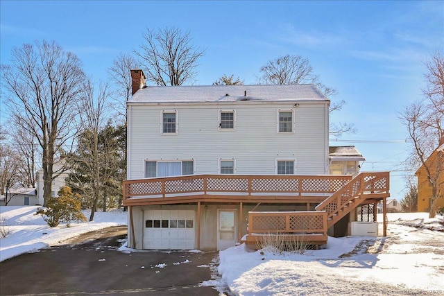 snow covered property featuring a deck, a chimney, and a garage